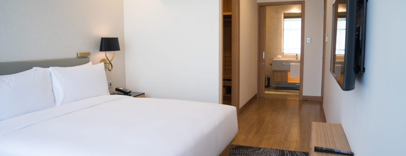 Small hotel room interior with double bed and bathroom